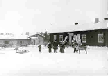 Män, kvinnor och barn samlade på gårdsplanen med renhudar på tork omkring 1915.