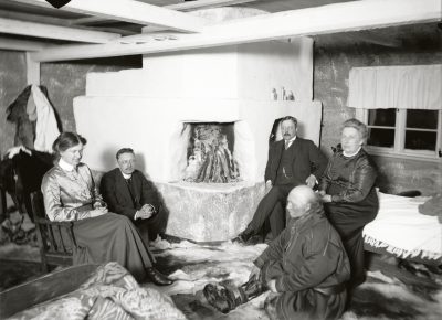 Sällskap vid brasan med bl.a. Emilie Demant Hatt till vänster och Johan Thuri sittandes på golvet.