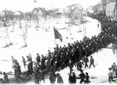 Demonstration med musikkår och fanor omkring 1910. Kanske nykterhetsrörelse p g a de vita blommorna i kavajslagen?