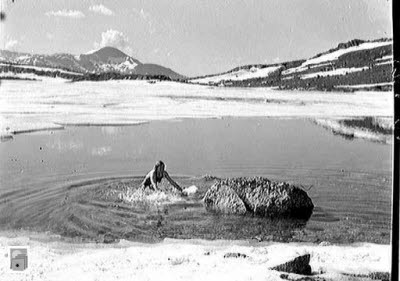 Han badar i en fjällsjö med is