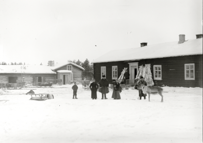 Män, kvinnor och barn samlade på gårdsplanen med renhudar på tork omkring 1915.