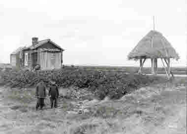 Två gossar framför potatislandet vid bostället i Tornedalen. Säden förvarades under halmtaket till höger. Foto från 1914.