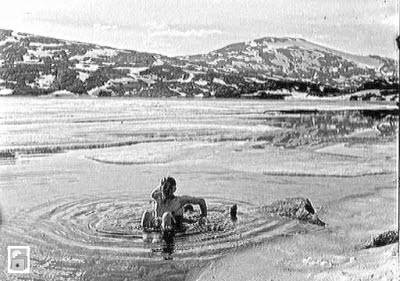 Han badar i en fjällsjö bland isflak